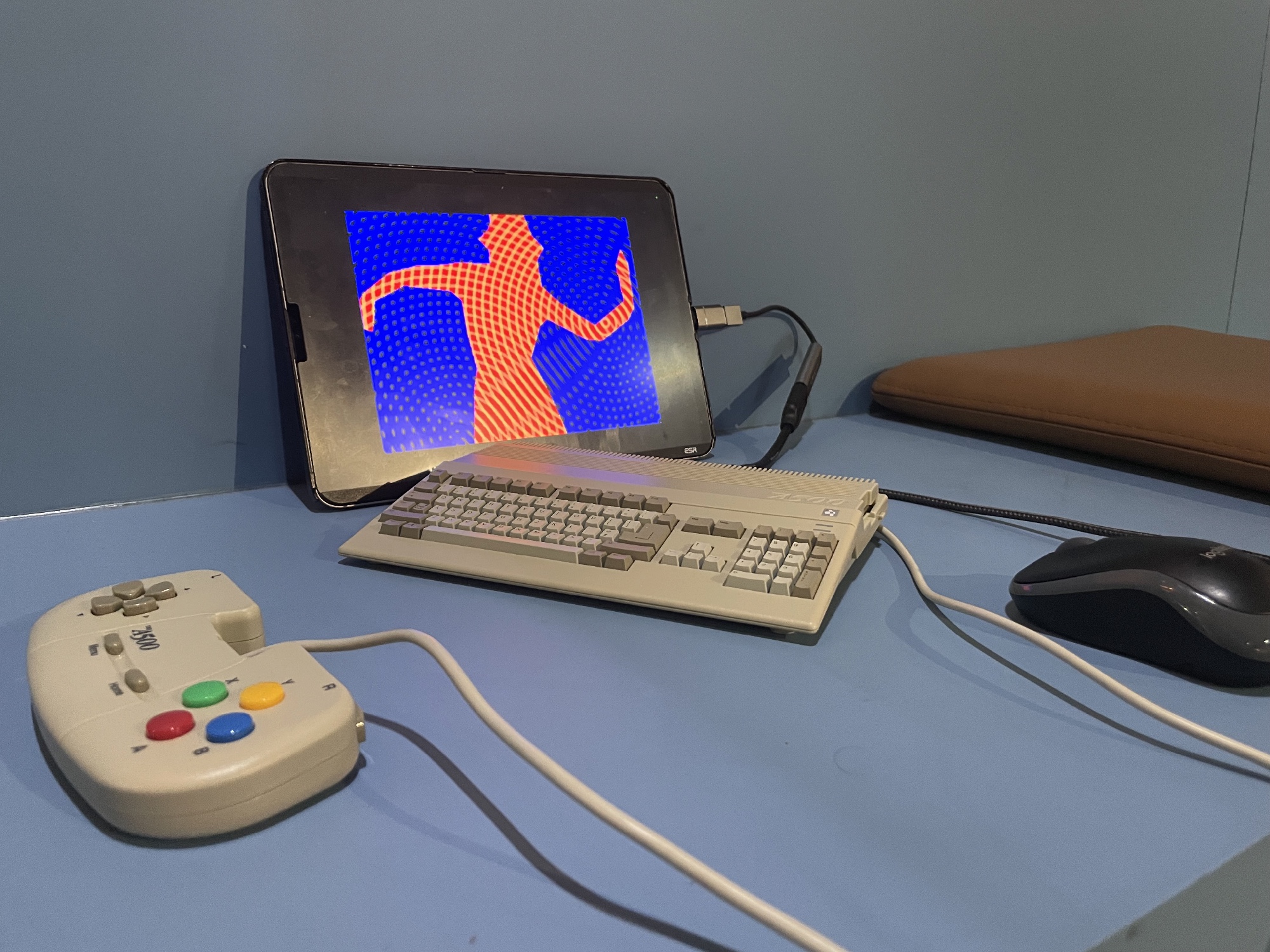 Photo of the A500 Mini on a blue background showing a
                silhoutted dancing figure from the demo State of the Art
                by Spaceballs