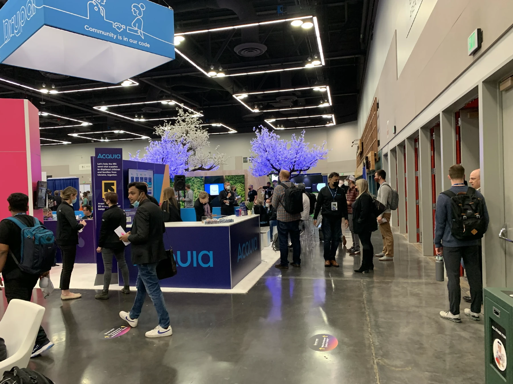 A large hall with rows of exhibition booths and attendees walking around