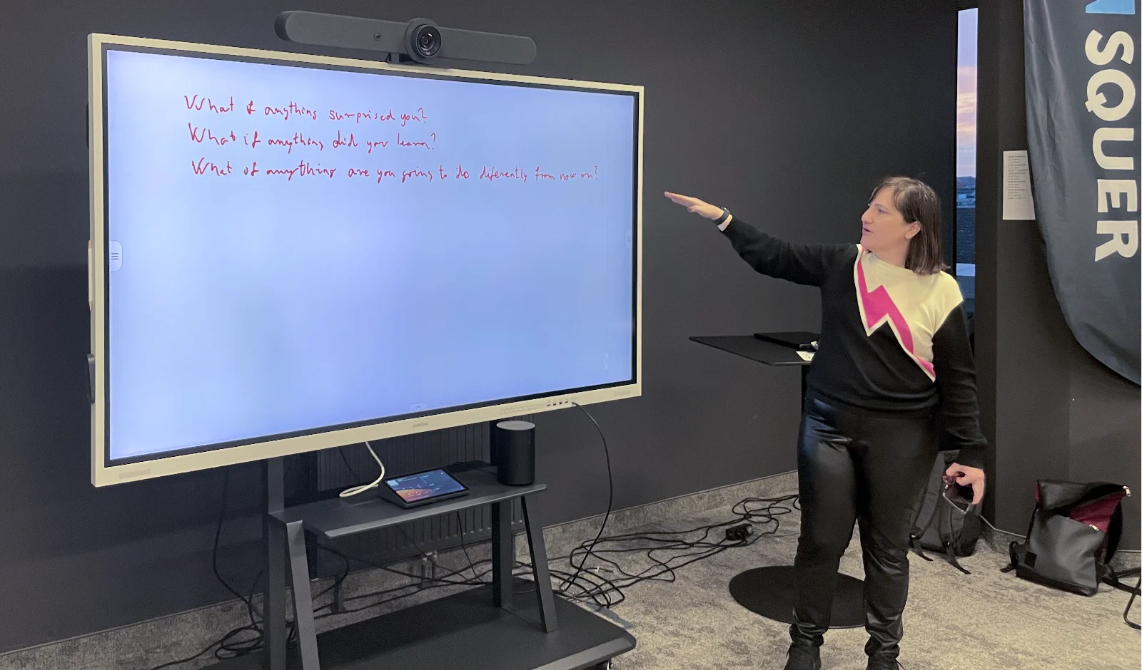 Ivett pointing at a screens showing three questions