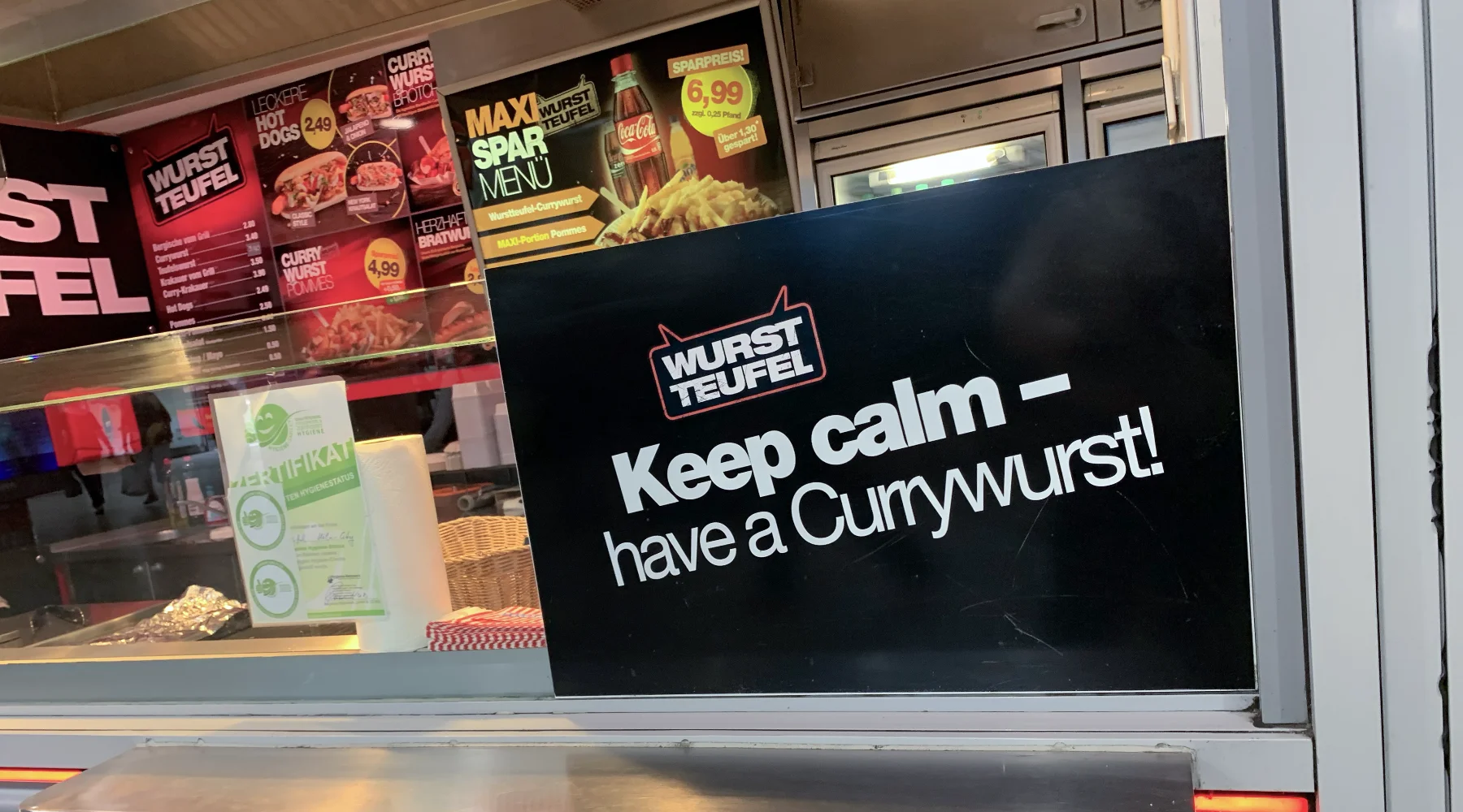 A food cart with a sign saying Calm Down, Have a Currywurst!