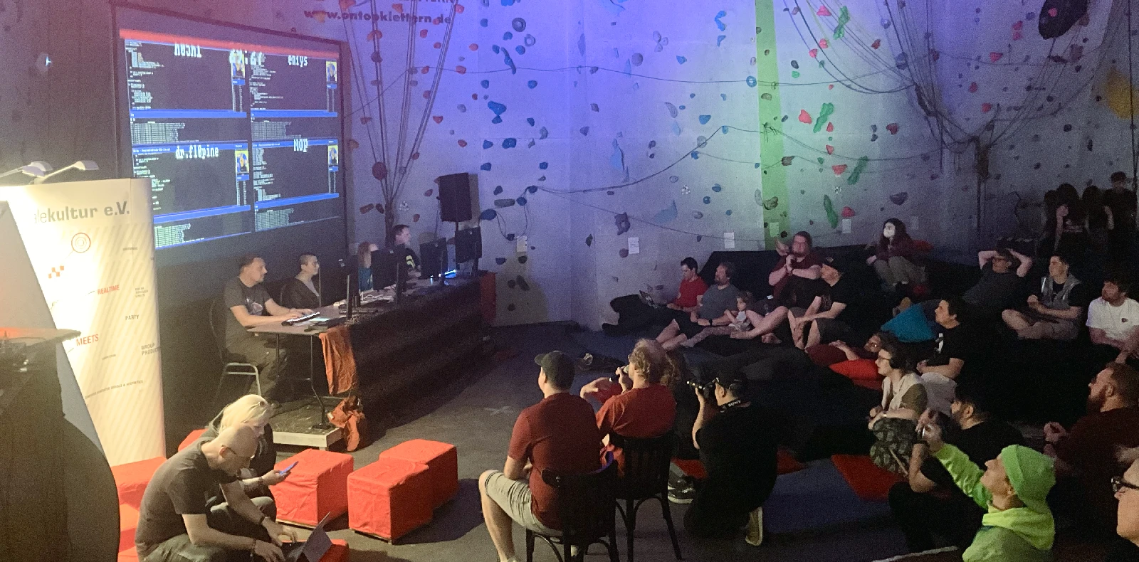 Contestants on stage at the Copper Showdown with a large screen showing their live code and its rendered output.