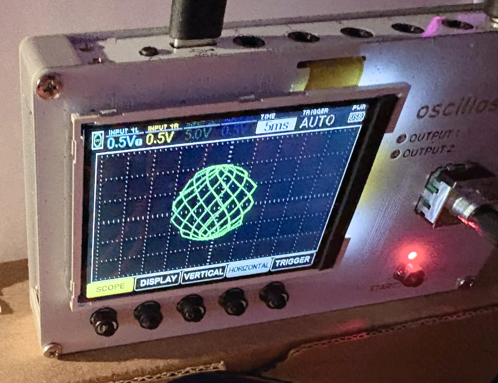 A close-up photo of the oscilloscope screen showing the bouncing ball.