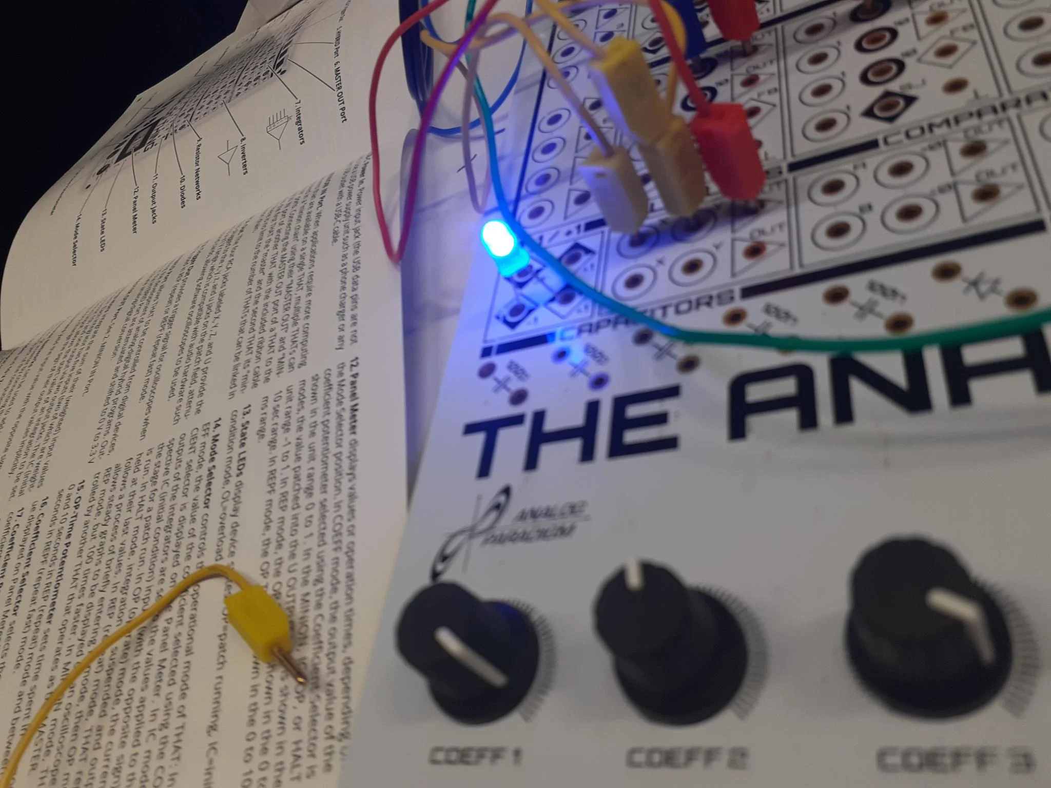 The Analog Thing analog computer patched with colored cables beside its printed manual.