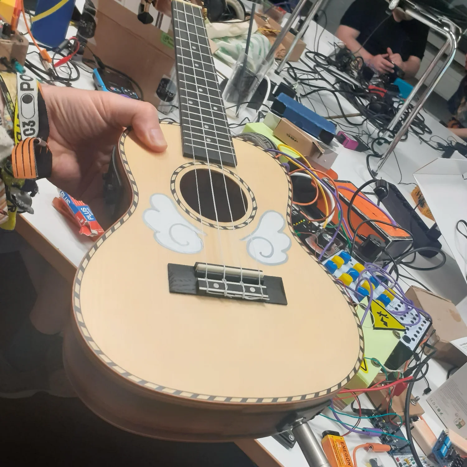 Hands holding an electric Ukulele, looks like a little guitar