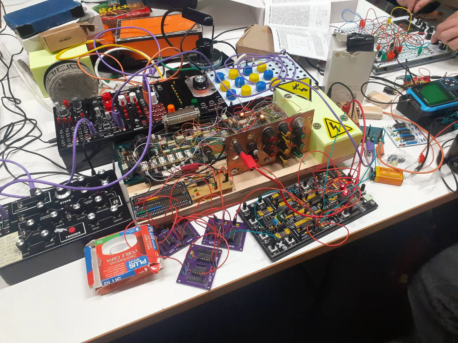 Workshop table covered with synthesizers, cables, and electronic equipment