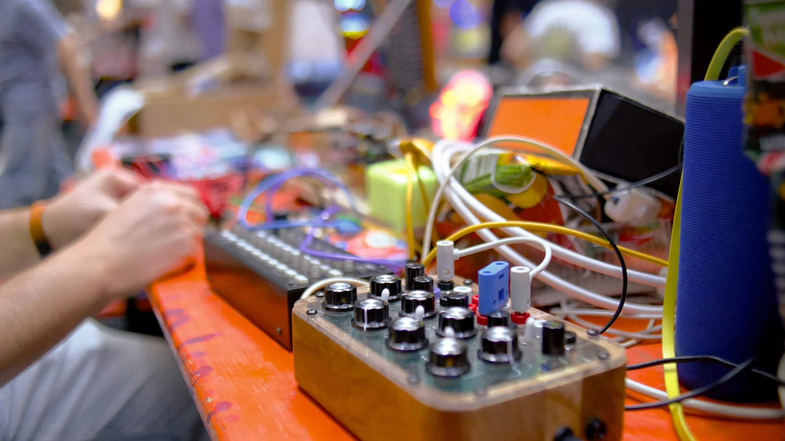 A custom Benjolin build on an orange workshop table, surrounded by colorful patch cables and a KORG SQ-1 STEP sequencer.
