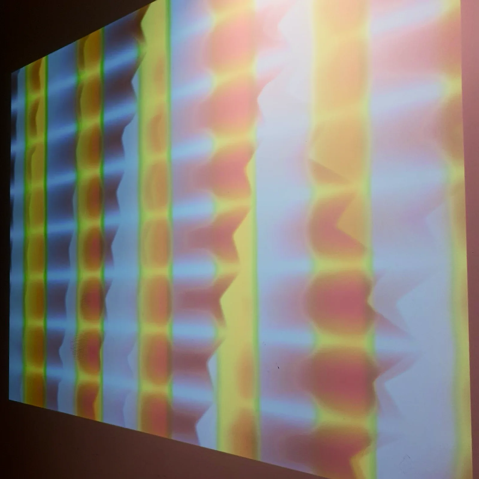 The projected colors of the video synthesizer on the wall