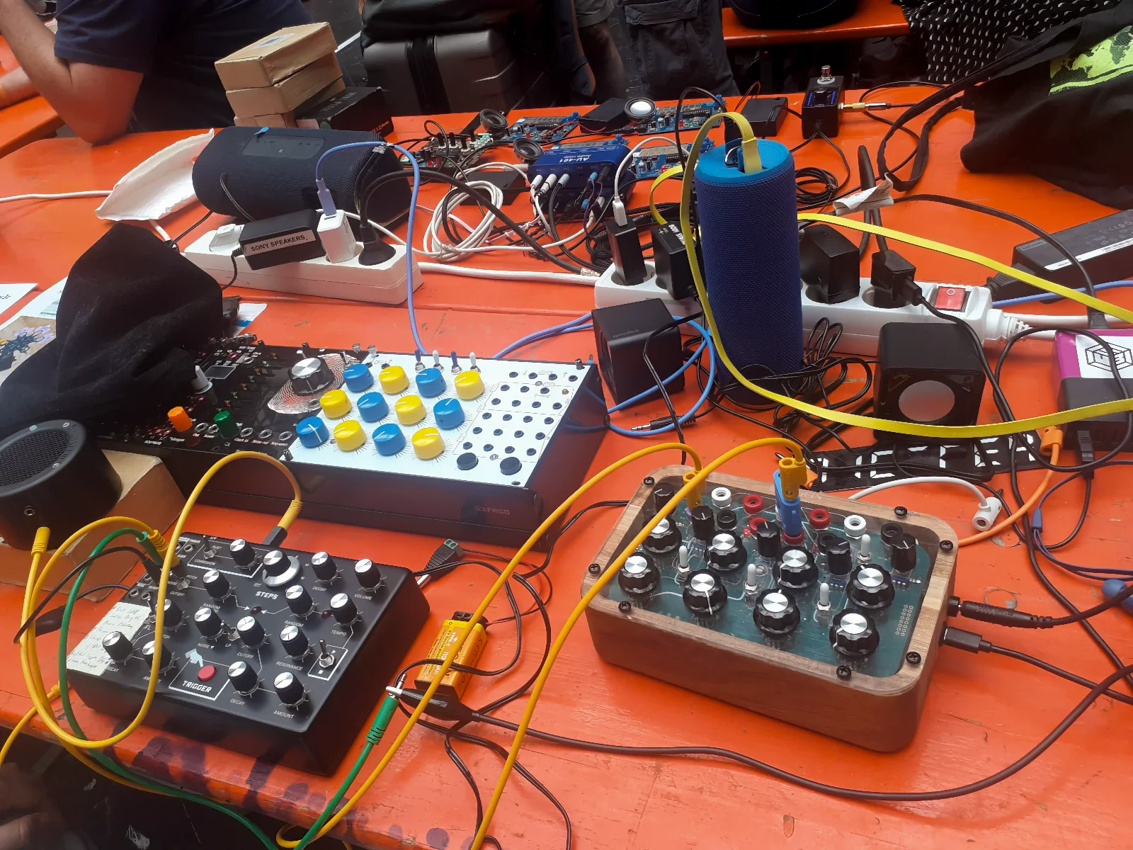 Orange table with synthesizers and patch cables being set up