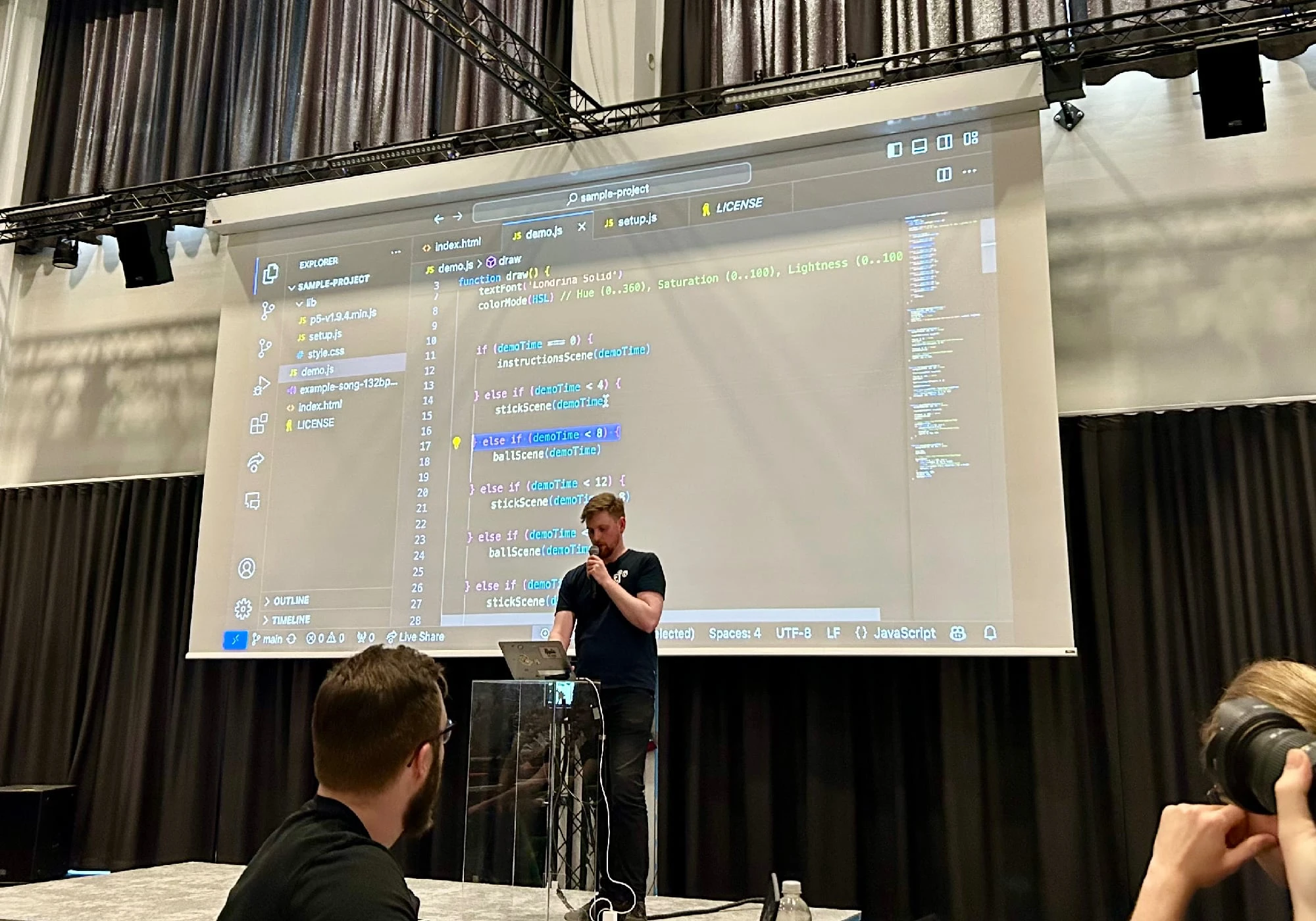 Felix standing on stage presenting the code sample projected behind him.