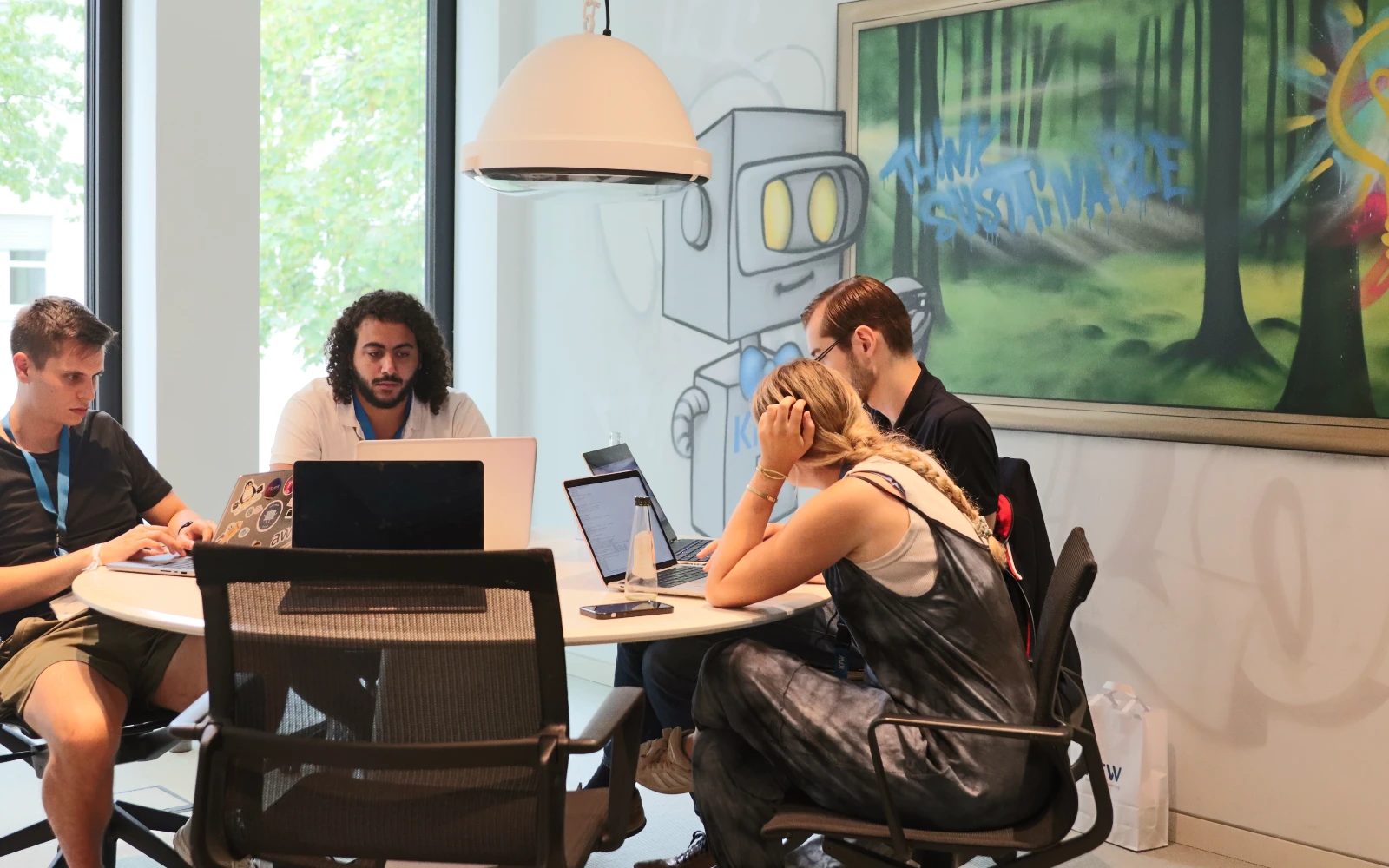 Four young people sitting and working together at a hackathon.