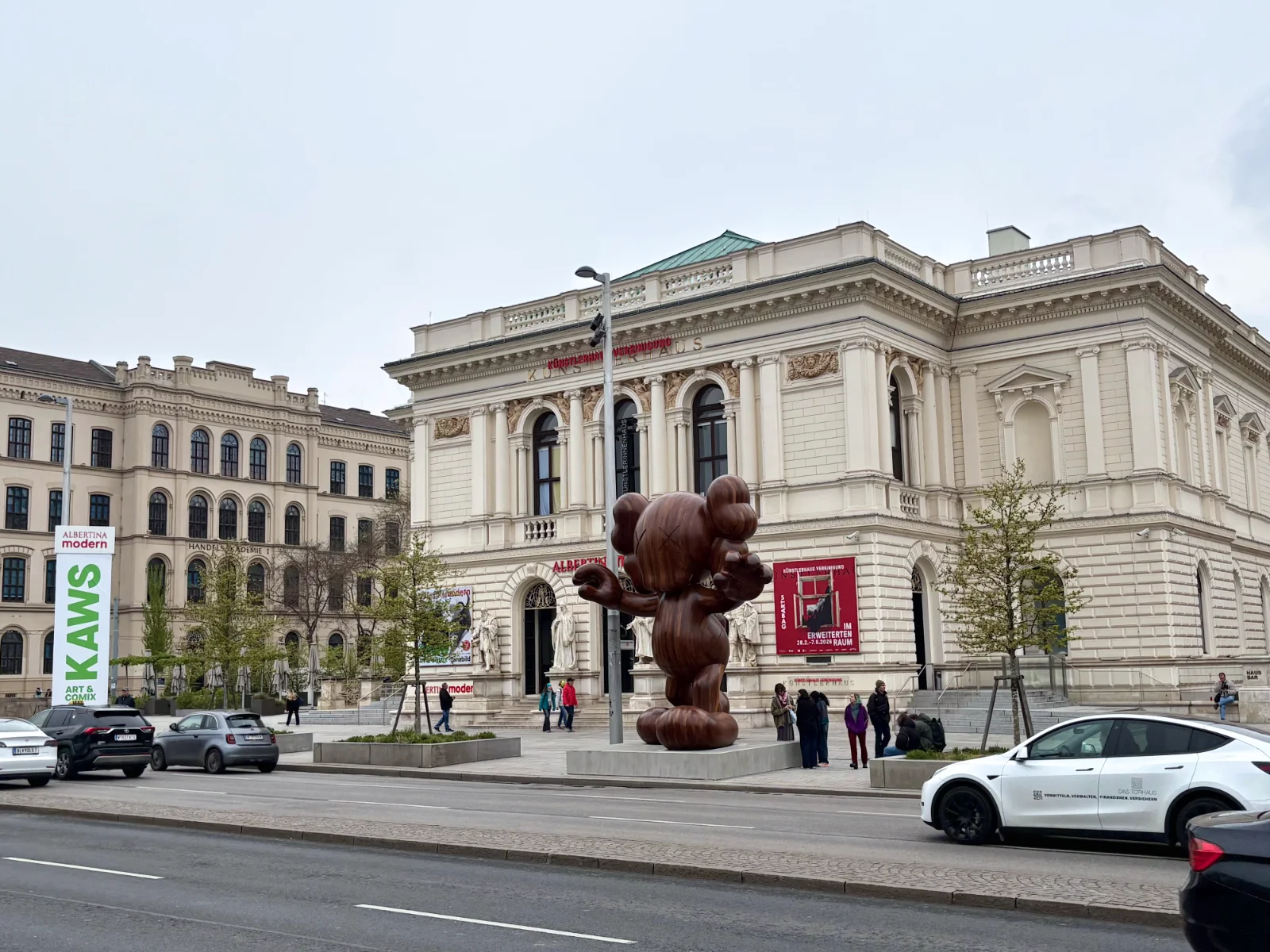 A monumental KAWS sculpture with crossed-out eyes standing in a large, white museum gallery.
