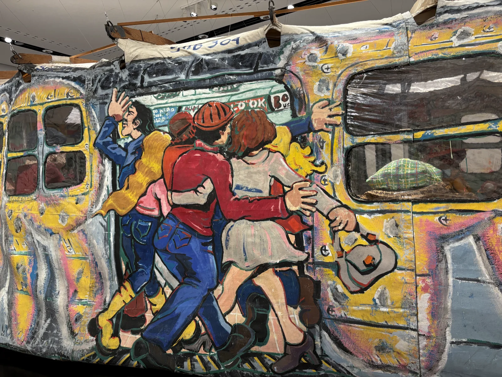 A close-up of exaggerated cartoon characters sitting on the benches of the subway installation.