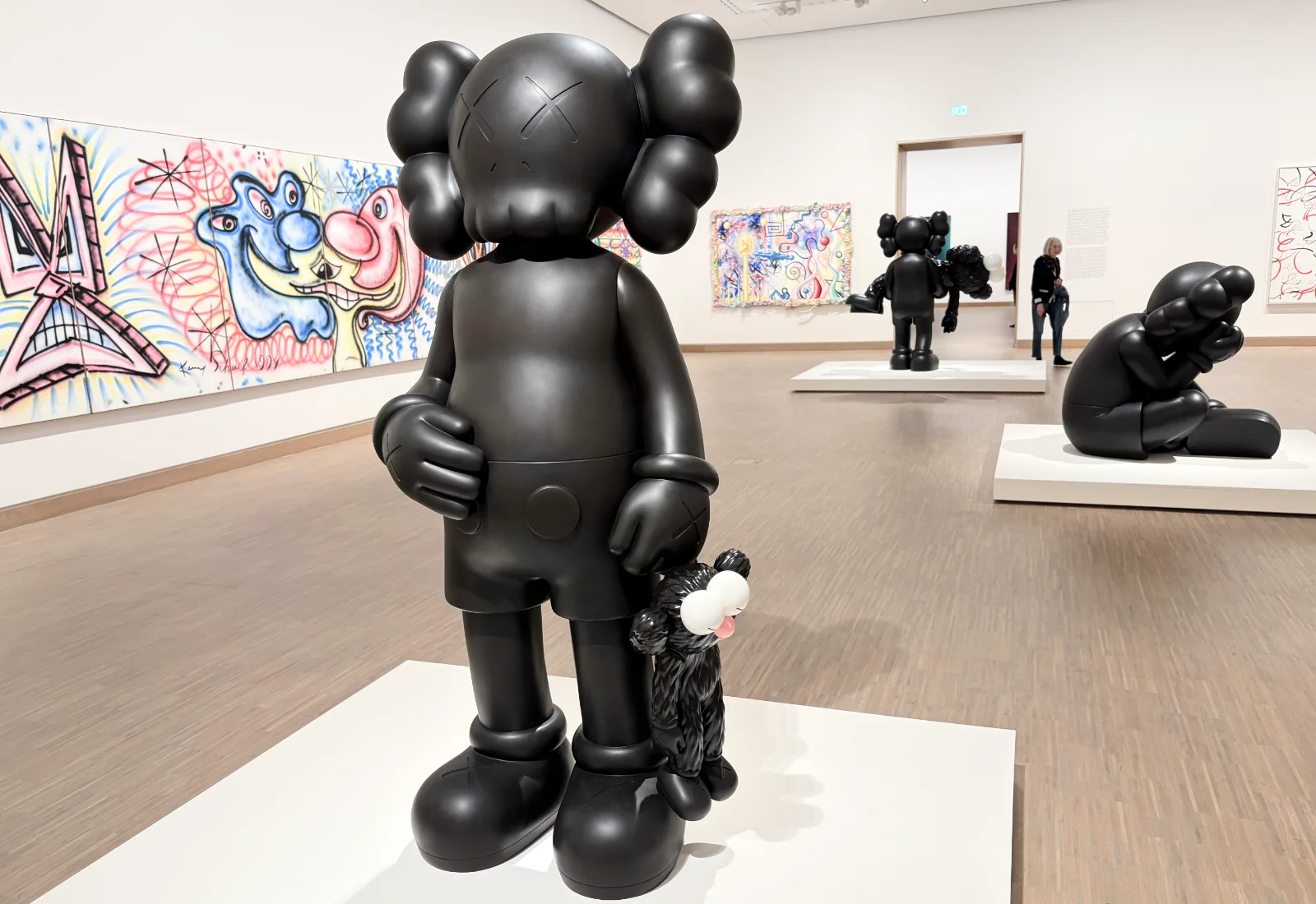 Three different artistic interpretations of Mickey Mouse displayed in a row on a museum wall.