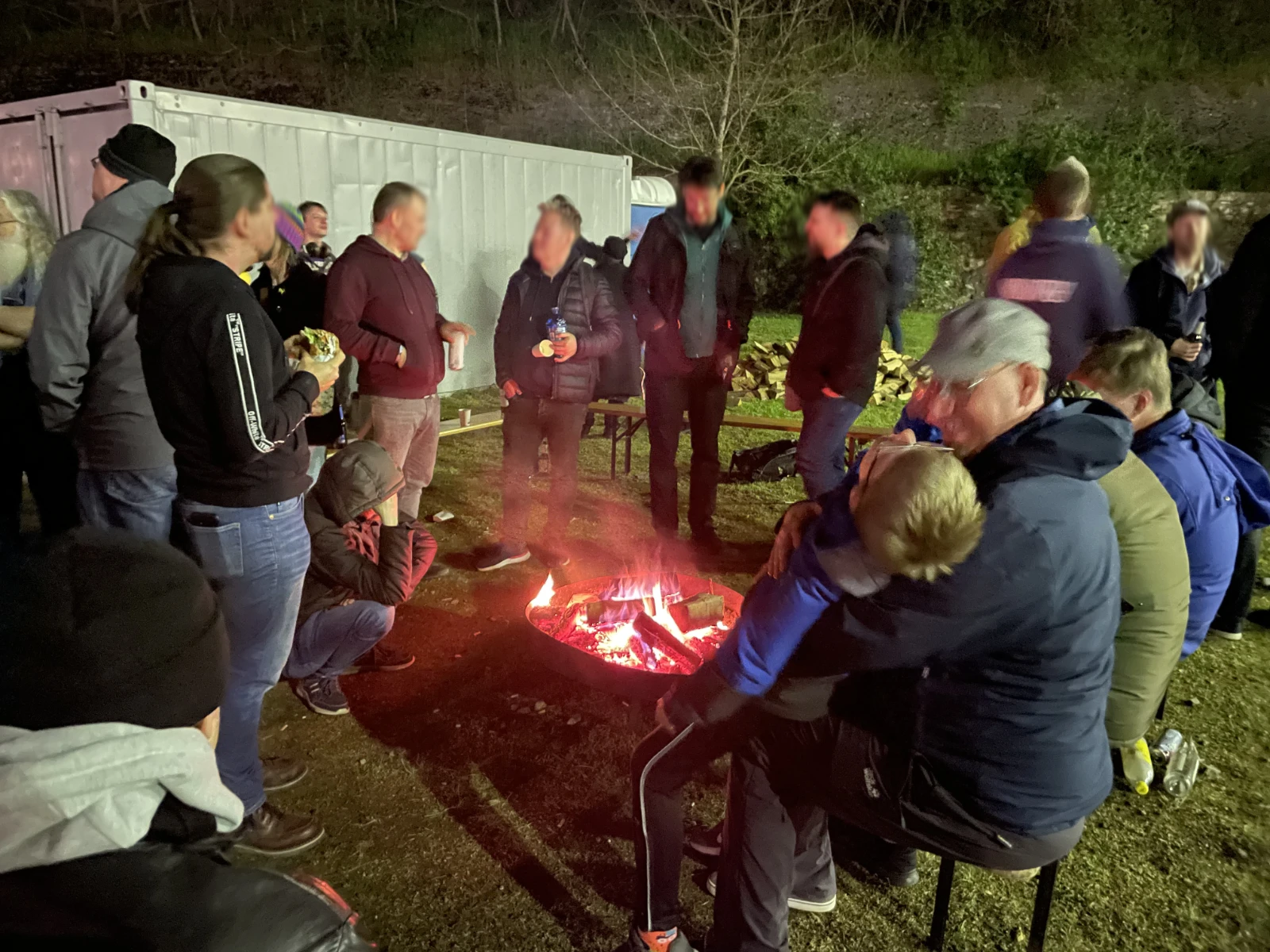 Sceners gathered around an outdoor fire area at night.