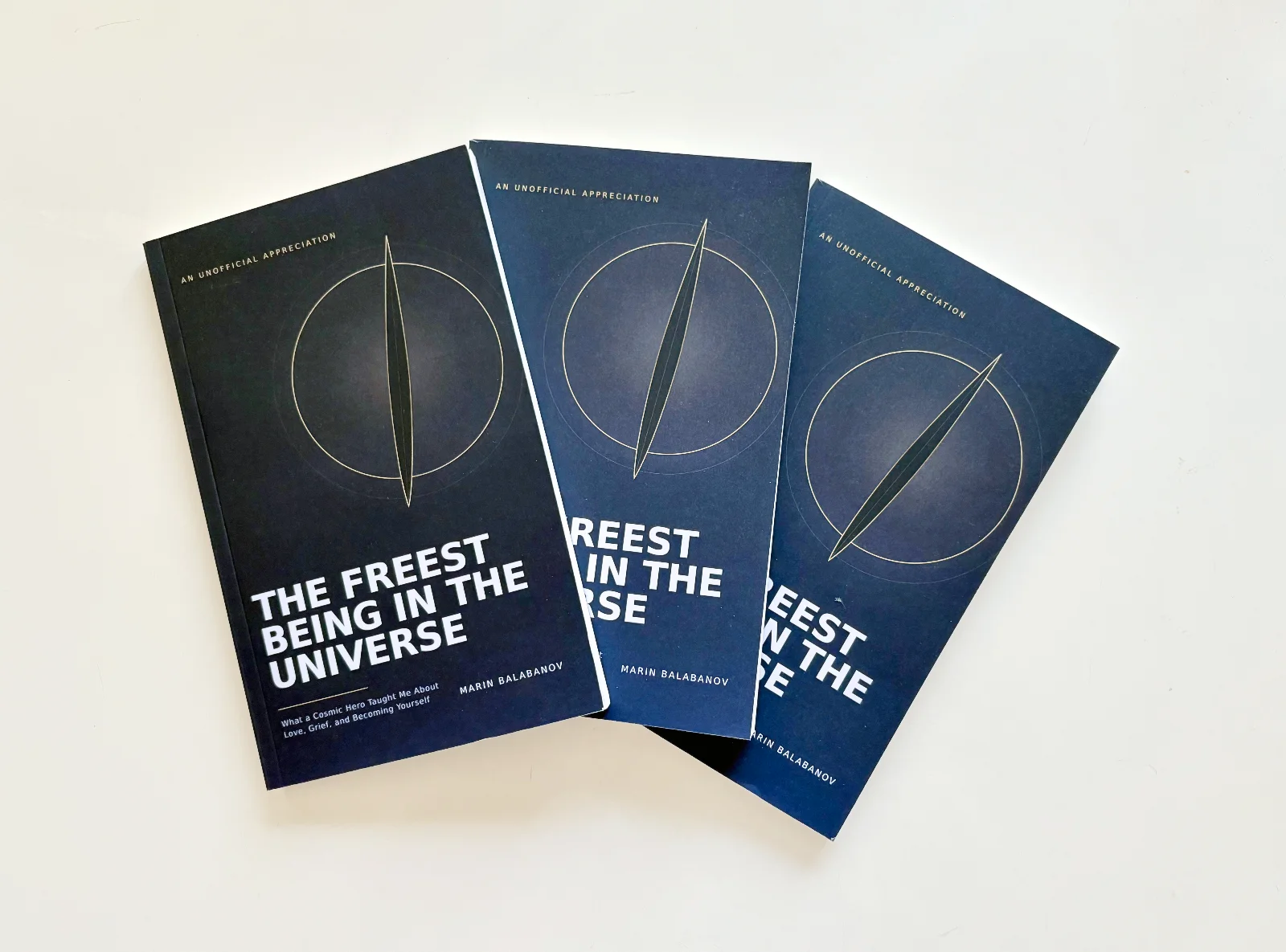 Printed paperback copies of The Freest Being in the Universe laid out on a table