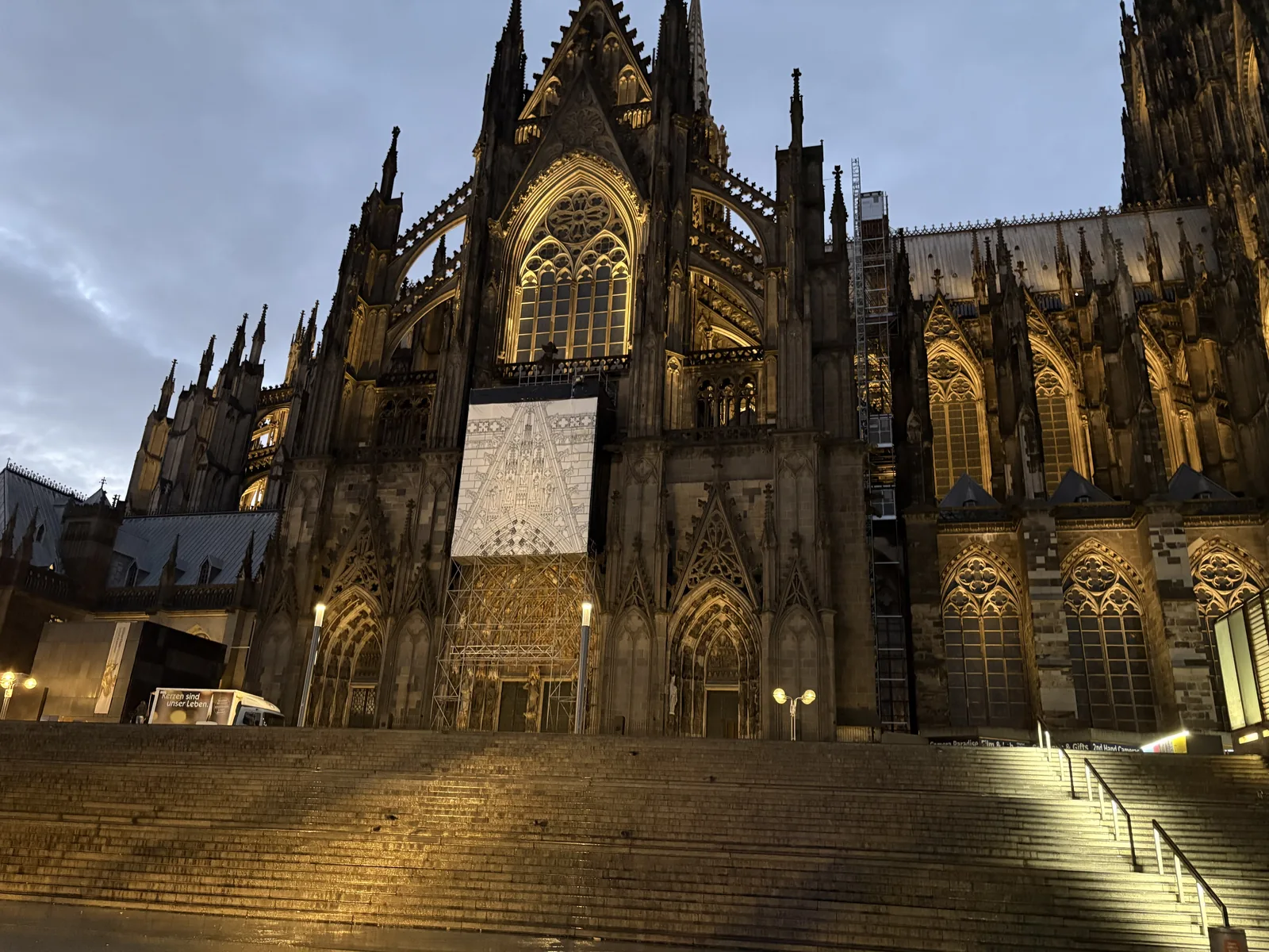 The illuminated Cologne Cathedral at dawn, seen from the steps below.
