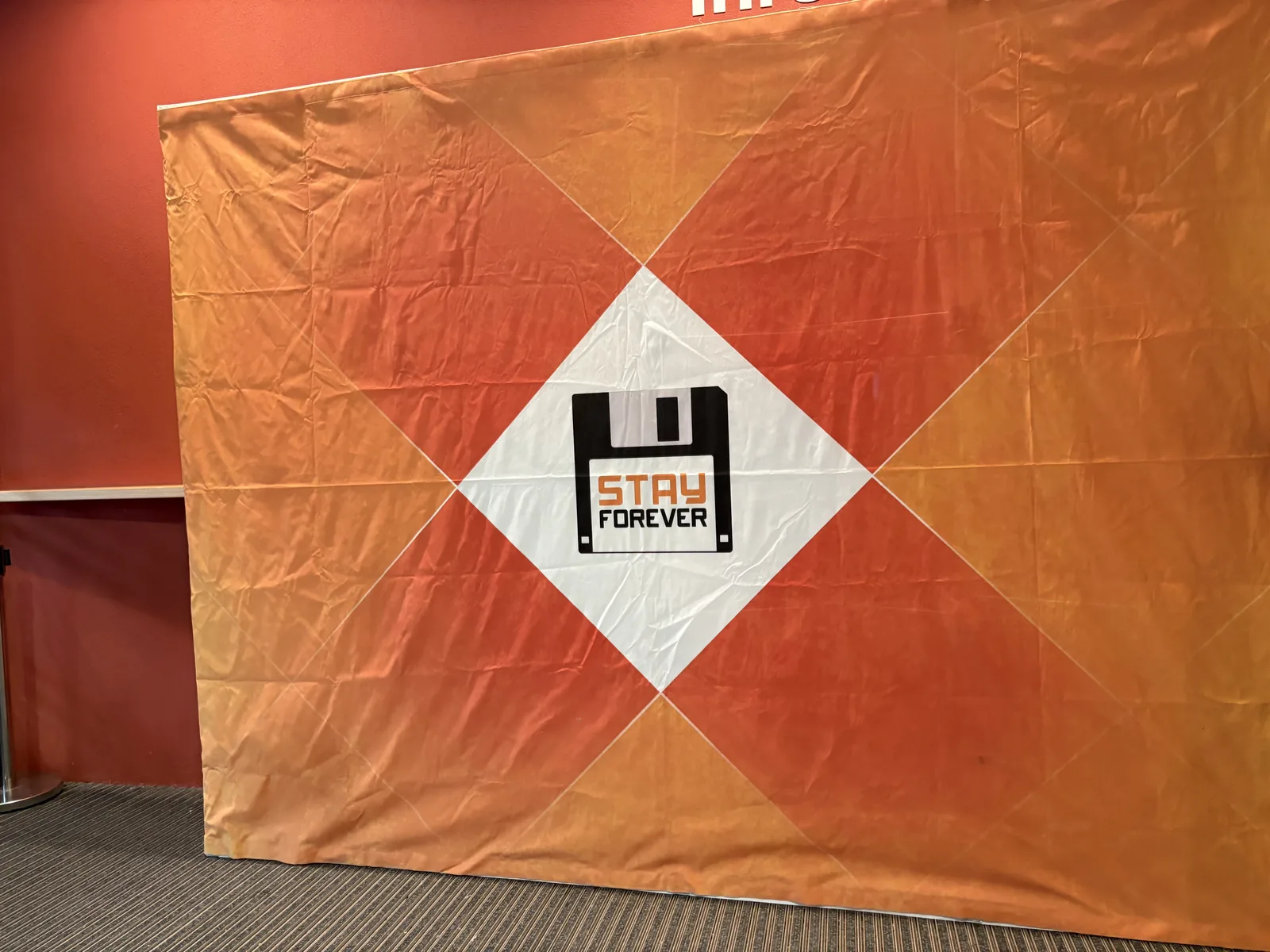 An orange banner with a white diamond showing the Stay Forever floppy disk logo.