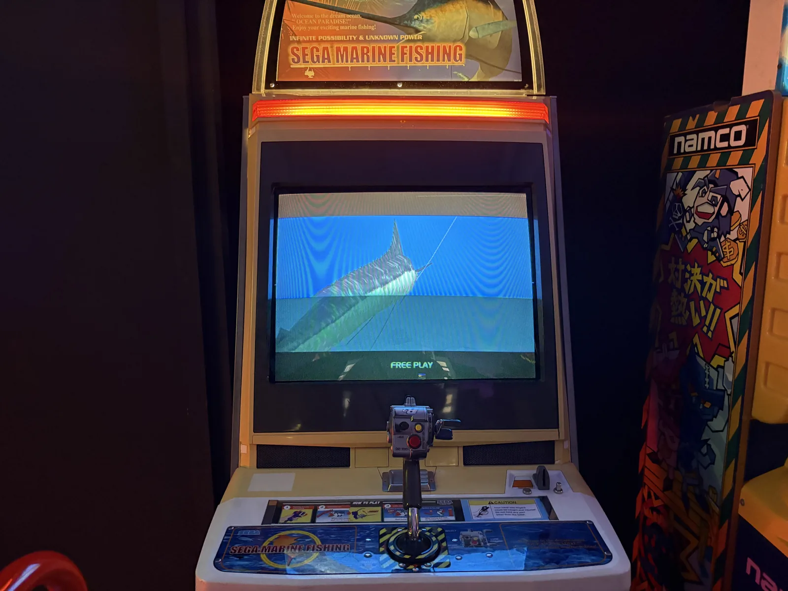 A Sega Marine Fishing arcade cabinet showing an underwater scene with a fish.