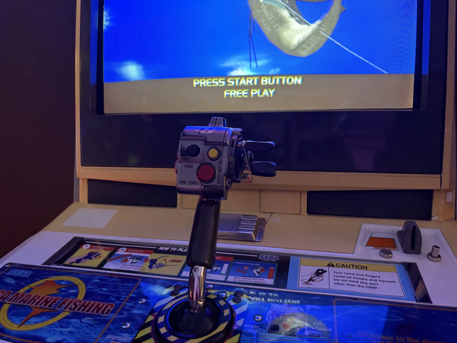 Close-up of the fishing rod controller with a reel mounted on the Sega Marine Fishing cabinet.
