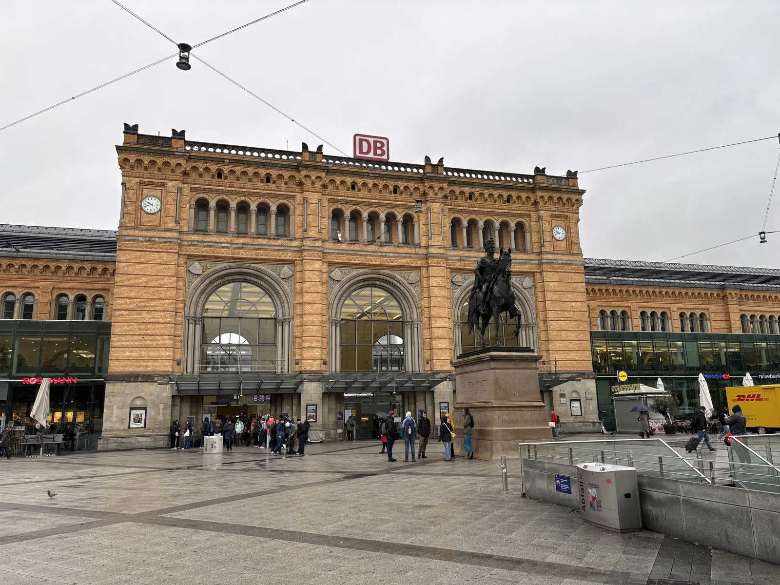 The yellow brick facade of Hanover's main train station with the equestrian statue of Ernst August in front.