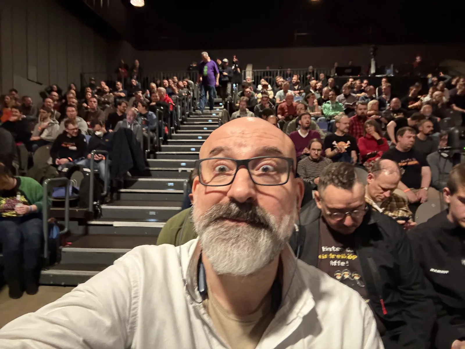 Marin taking a selfie in front of the tiered rows of a packed audience.
