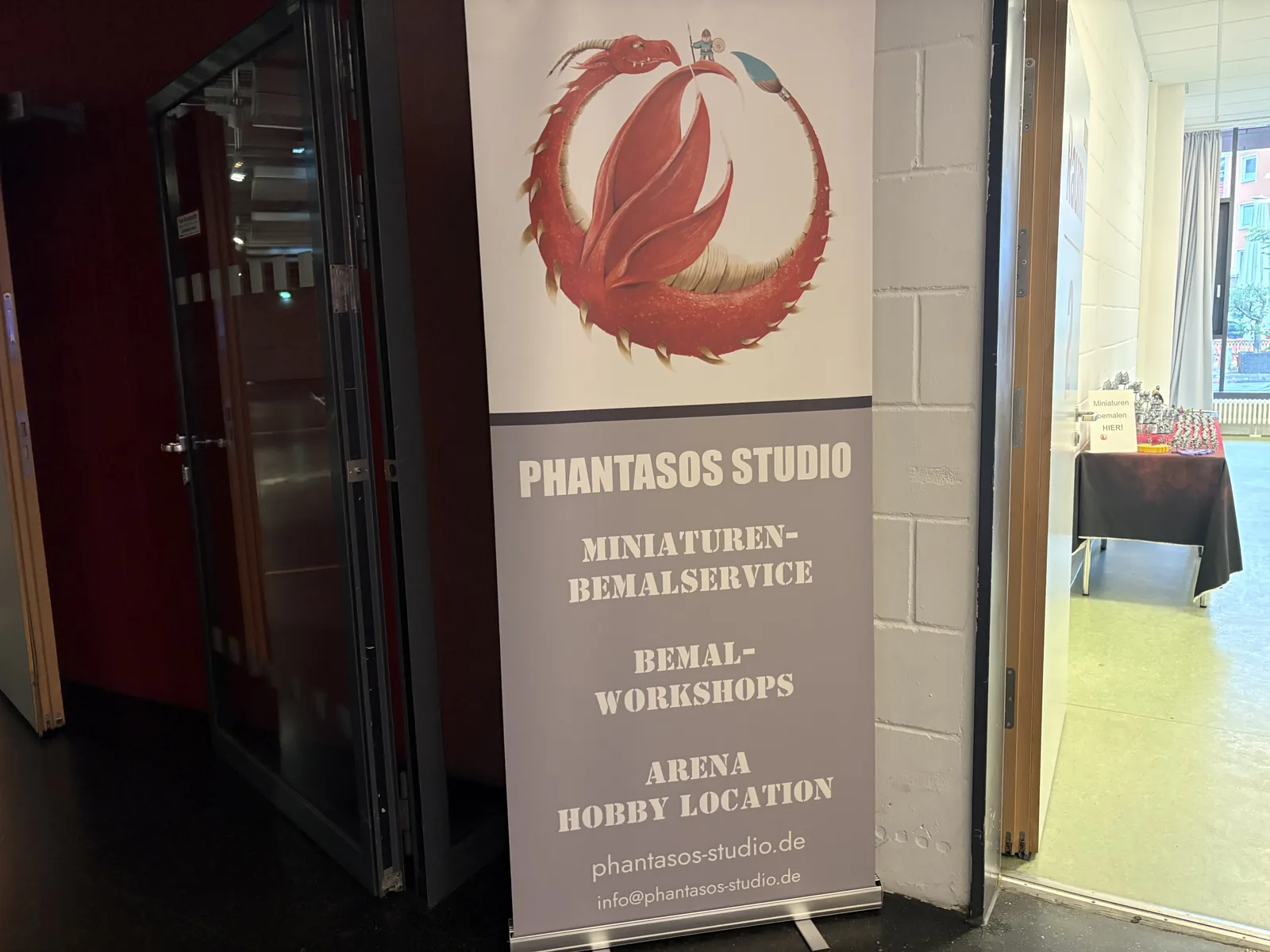 A roll-up banner for Phantasos Studio advertising miniature painting service and workshops.