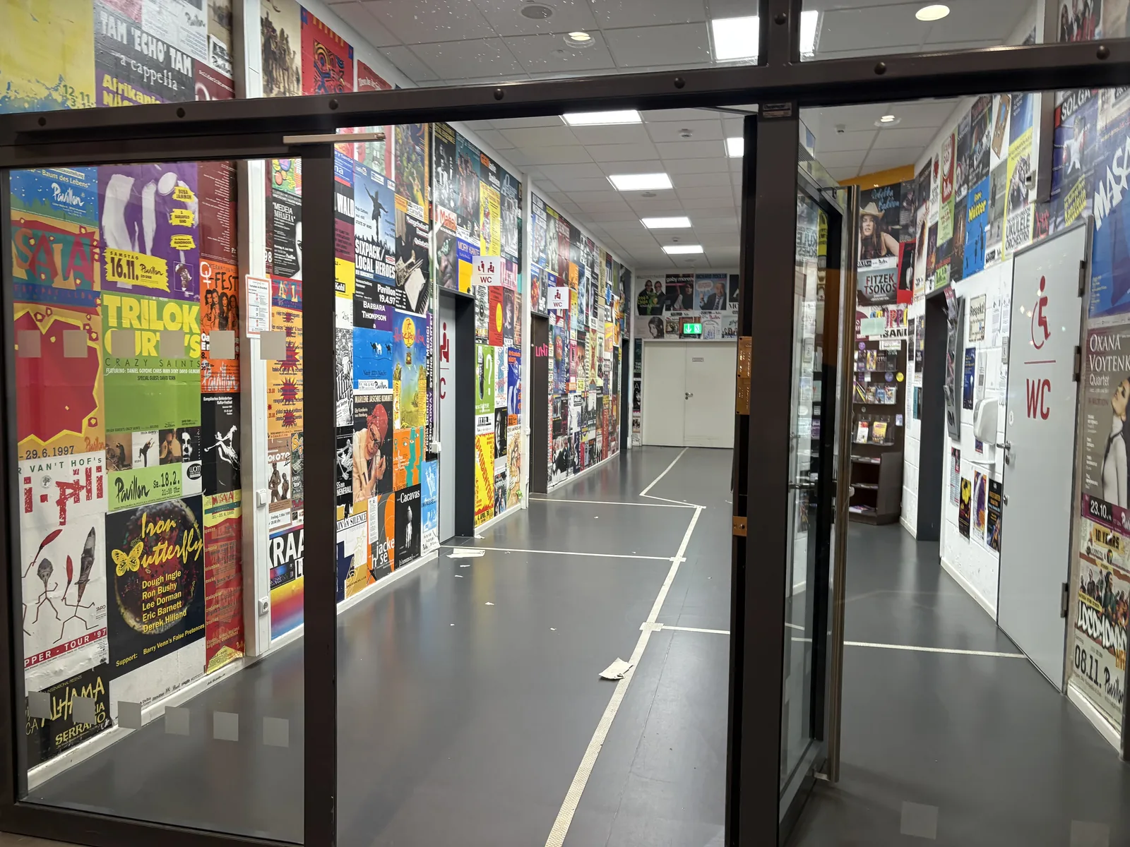 A long corridor whose walls are completely covered in colorful concert posters.